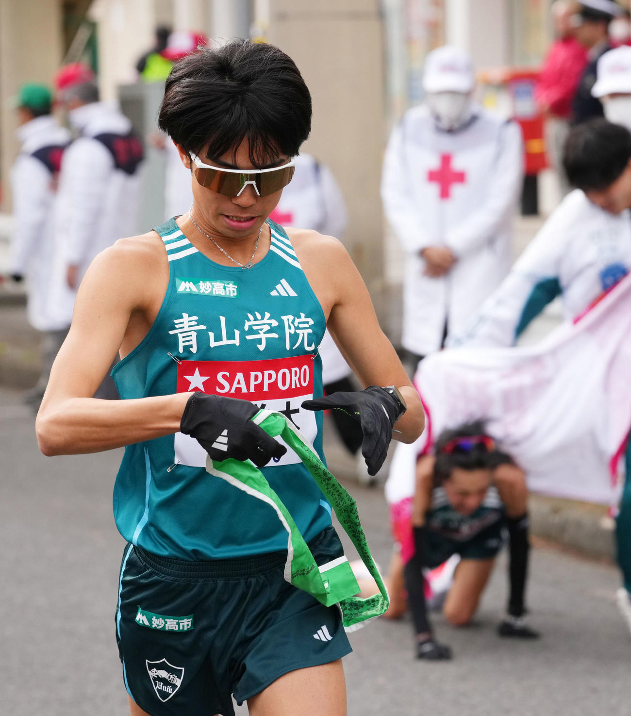 鶴見中継所で青学大9区倉本（右）からたすきを受け走り出す10区宇田川（撮影・横山健太）