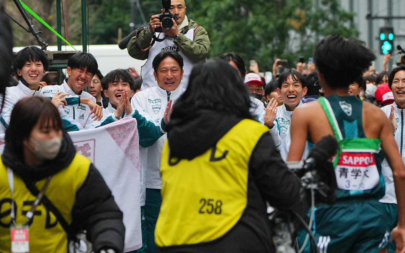 優勝のゴールテープを切った青学大10区宇田川（手前）を笑顔で出迎える原監督（左から4人目）ら選手たち（撮影・垰建太）