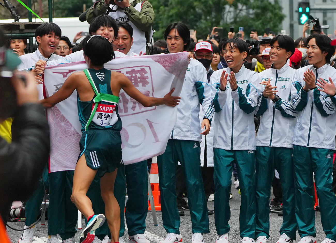 優勝のゴールテープを切った青学大10区宇田川（左から2人目）を笑顔で出迎える原監督（同4人目）ら選手たち（撮影・垰建太）