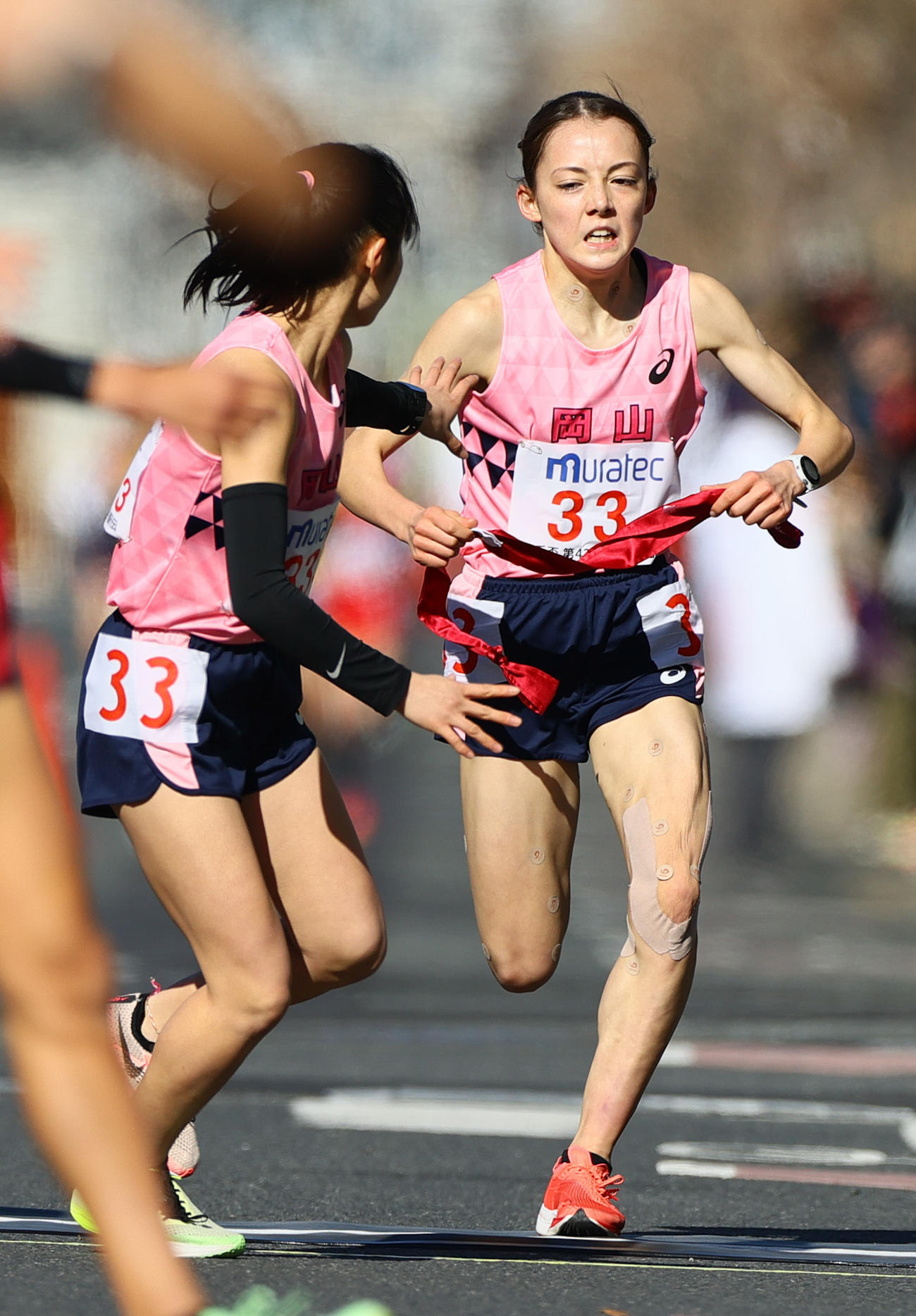 岡山3区黒田六花（手前）にたすきをつなぐ2区のドルーリー朱瑛里（撮影・上山淳一）