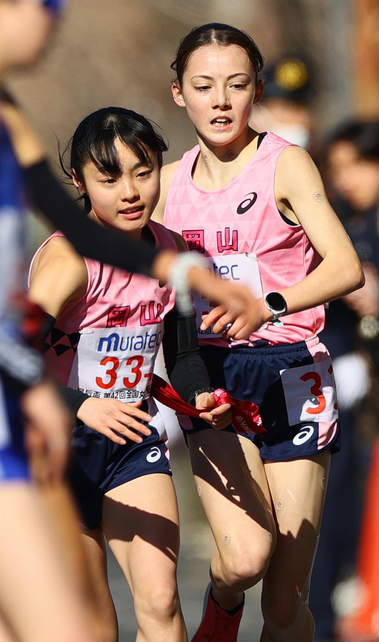 岡山3区黒田六花（手前）にたすきをつなぐ2区のドルーリー朱瑛里（撮影・上山淳一）