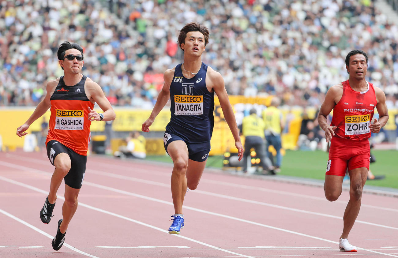男子100メートル予選1組目で1位の柳田大輝（中央）。左は東田旺洋、右はラル・ムハンマド・ゾフリ）（代表撮影）