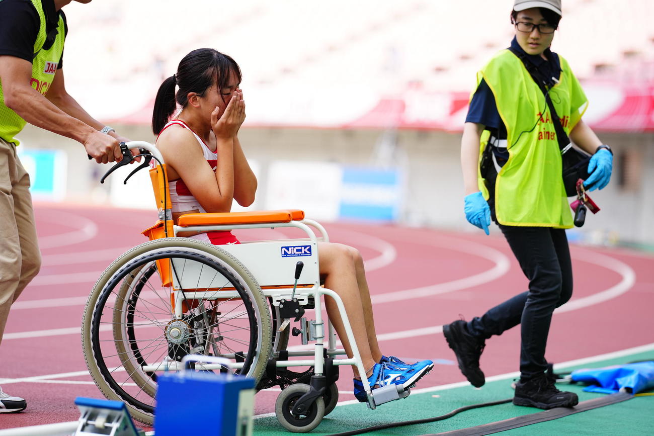 日本陸上選手権　女子100メートル予選、レースを終え涙をぬぐいながら車いすで引き揚げる山形（撮影・垰建太）