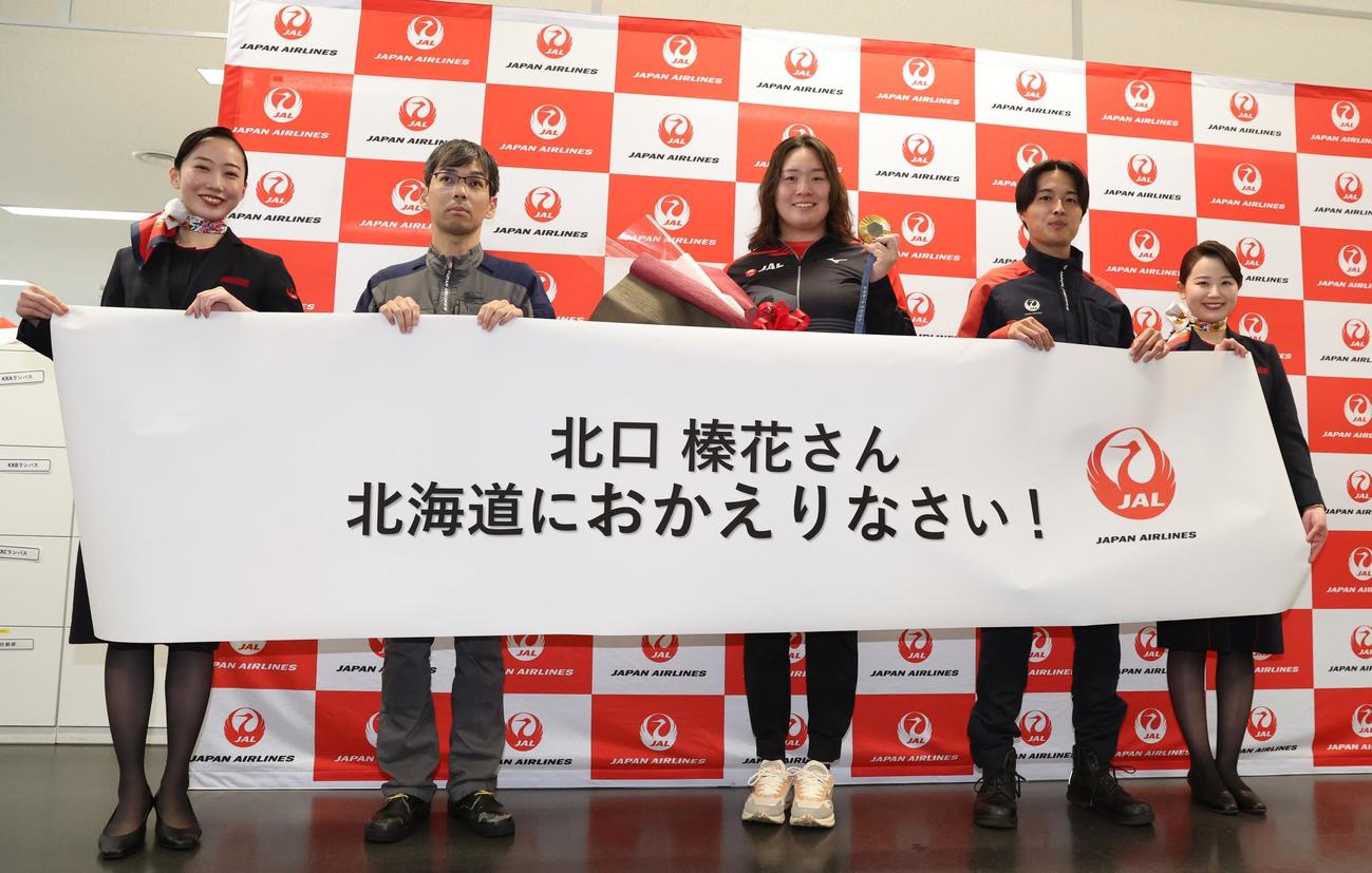新千歳空港でJALのスタッフに出迎えられるやり投げの北口（中央）（撮影・黒川智章）