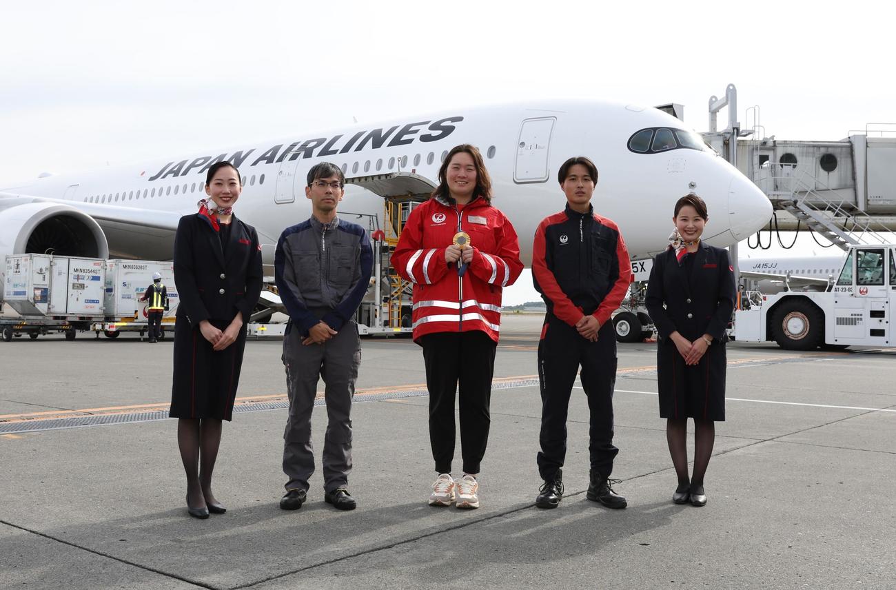 新千歳空港でJAL機の前でスタッフと記念撮影するやり投げの北口（中央）（撮影・黒川智章）