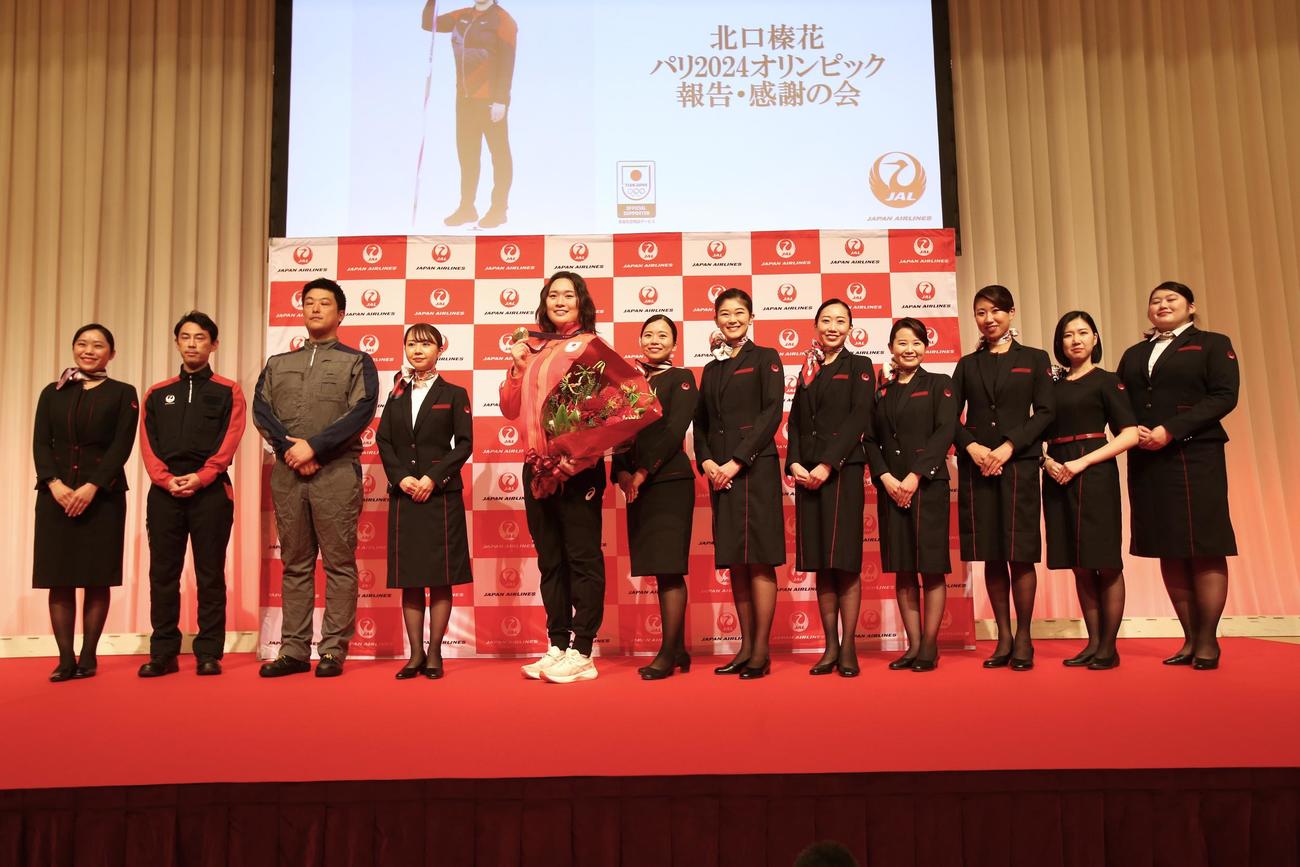 北口（左から5人目）は、金メダルを掲げて日本航空のCAら職員と一緒に笑顔（撮影・中島洋尚）