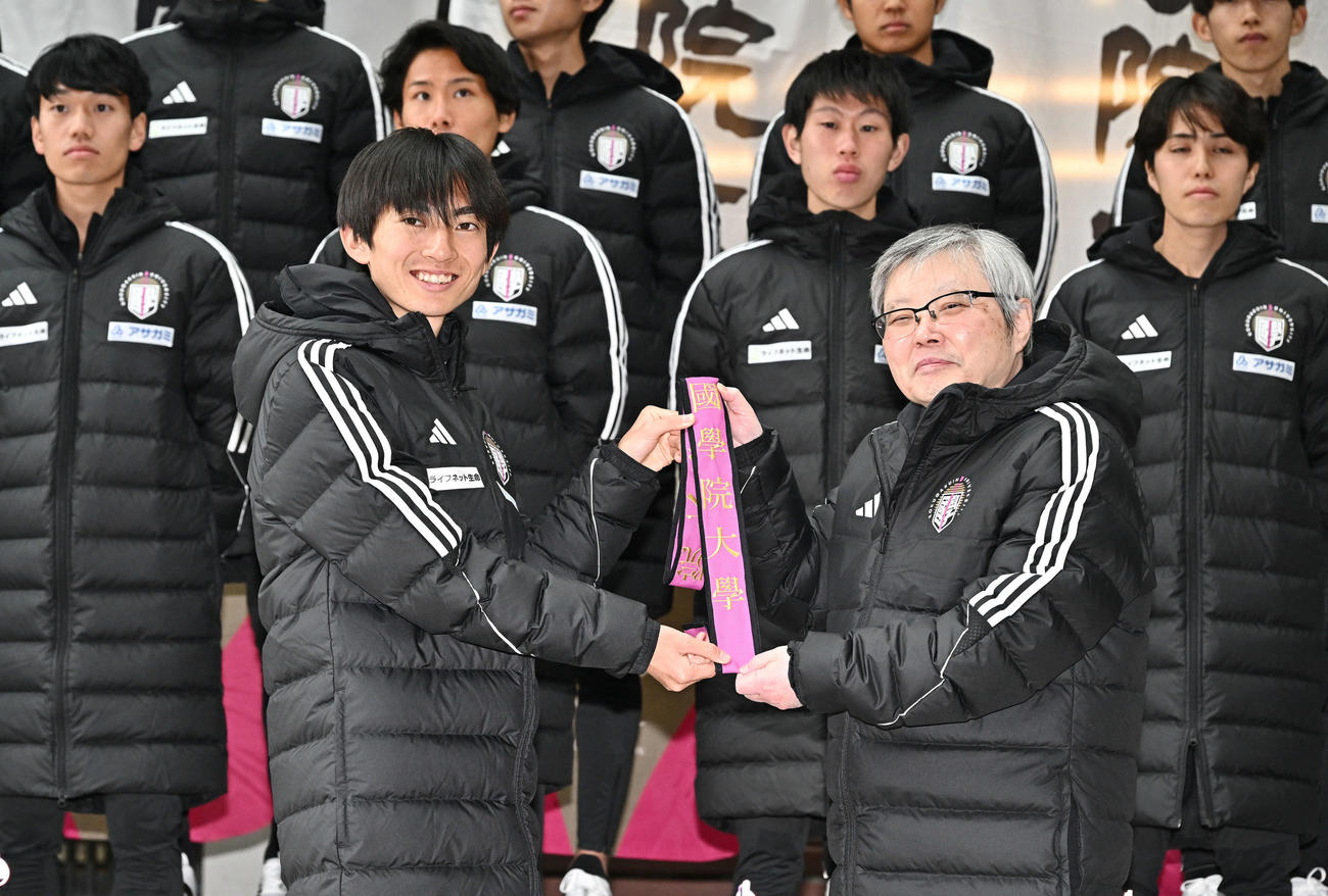 国学院大・針本正行学長（手前右）からたすきを受け取る平林（撮影・滝沢徹郎）