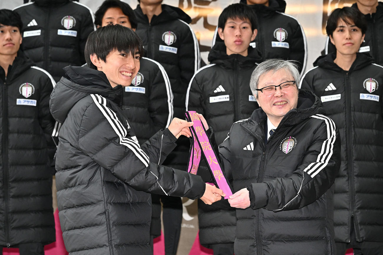 国学院大・針本正行学長（手前右）からたすきを受け取る平林（撮影・滝沢徹郎）