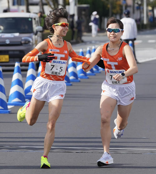 富士山女子駅伝　中継場で拓大6区門脇奈穂（右）にたすきを渡す5区不破聖衣来（左）（撮影・垰建太）