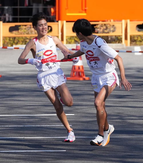 中大4区白川（左）は5区園木に小田原中継所トップでたすきを渡す（撮影・鈴木みどり）
