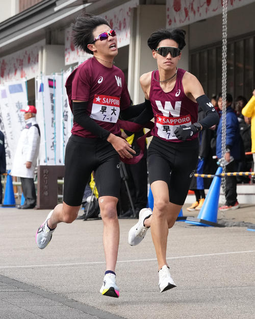早大6区山崎（左）は7区伊藤に小田原中継所でたすきを渡す（撮影・鈴木みどり）
