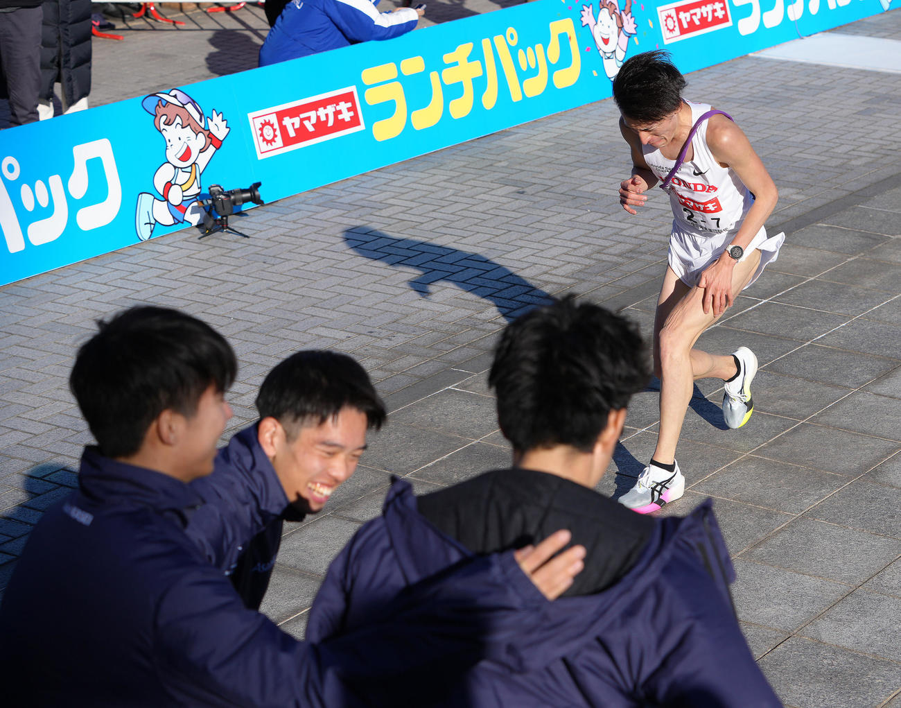 2位でゴールしたHonda7区中山。手前は優勝を喜ぶ旭化成の選手たち（撮影・足立雅史）
