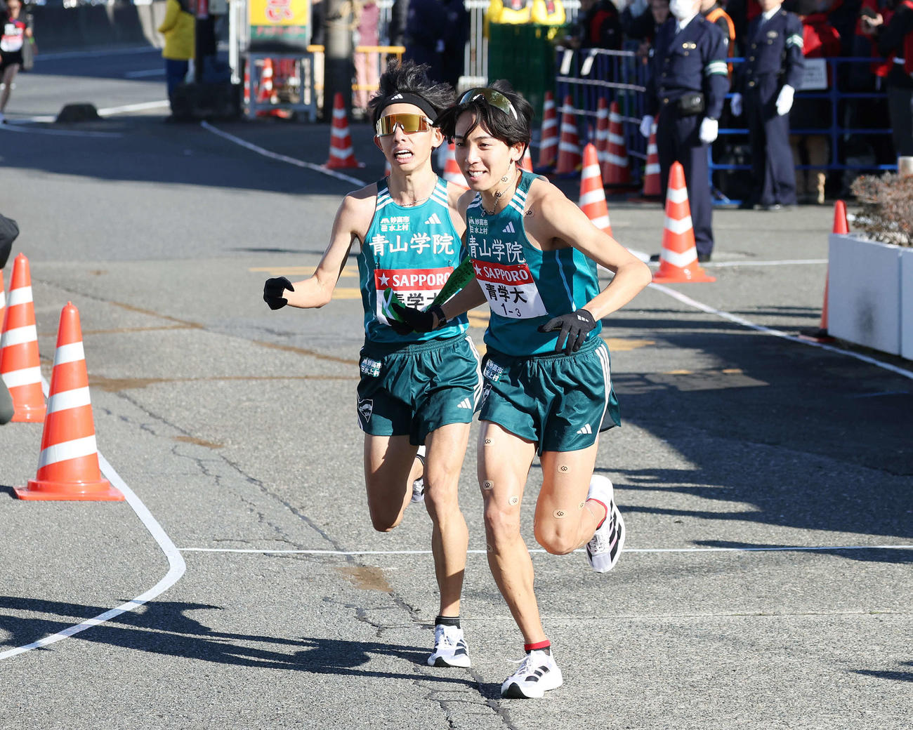 戸塚中継所で青学大3区鶴川（右）は3位で2区黒田朝日からタスキを受け駆け出す（撮影・宮地輝）