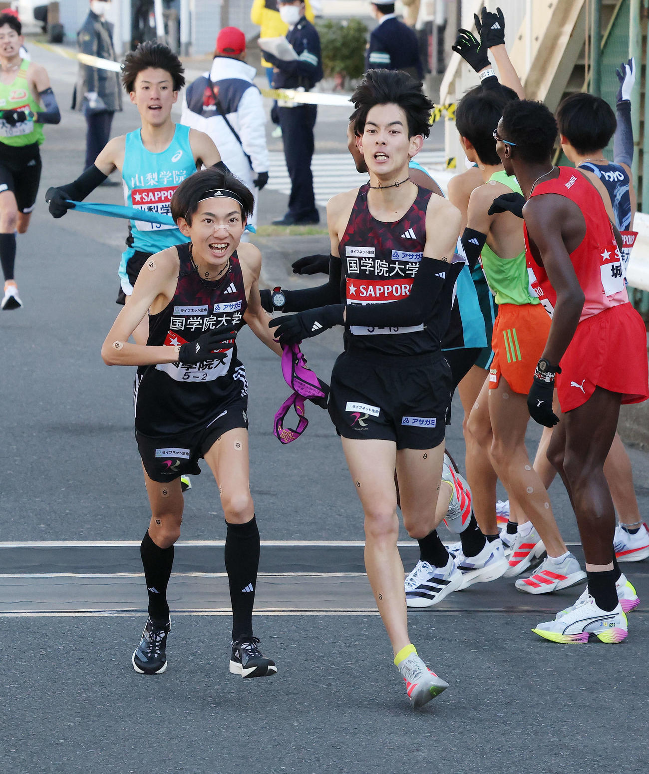 鶴見中継所を6位でタスキリレーする国学院大1区野中（右）と2区平林（撮影・河田真司）