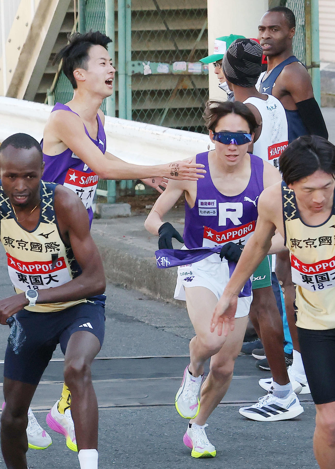 鶴見中継所を16位でタスキリレーする立大1区吉屋（左）と2区馬場（撮影・河田真司）