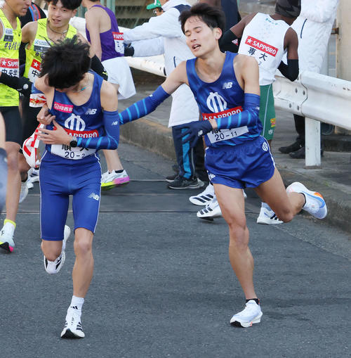 鶴見中継所を12位でタスキリレーする順大1区浅井（右）と2区玉目（撮影・河田真司）