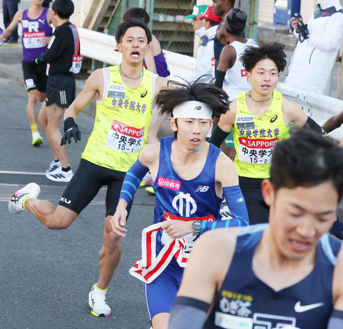 鶴見中継所を13位でタスキリレーする中央学院第1区堀田（後方左）と2区吉田（撮影・河田真司）