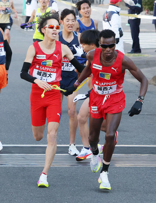 鶴見中継所を9位でタスキリレーする城西大1区久保出（左）と2区キムタイ（撮影・河田真司）