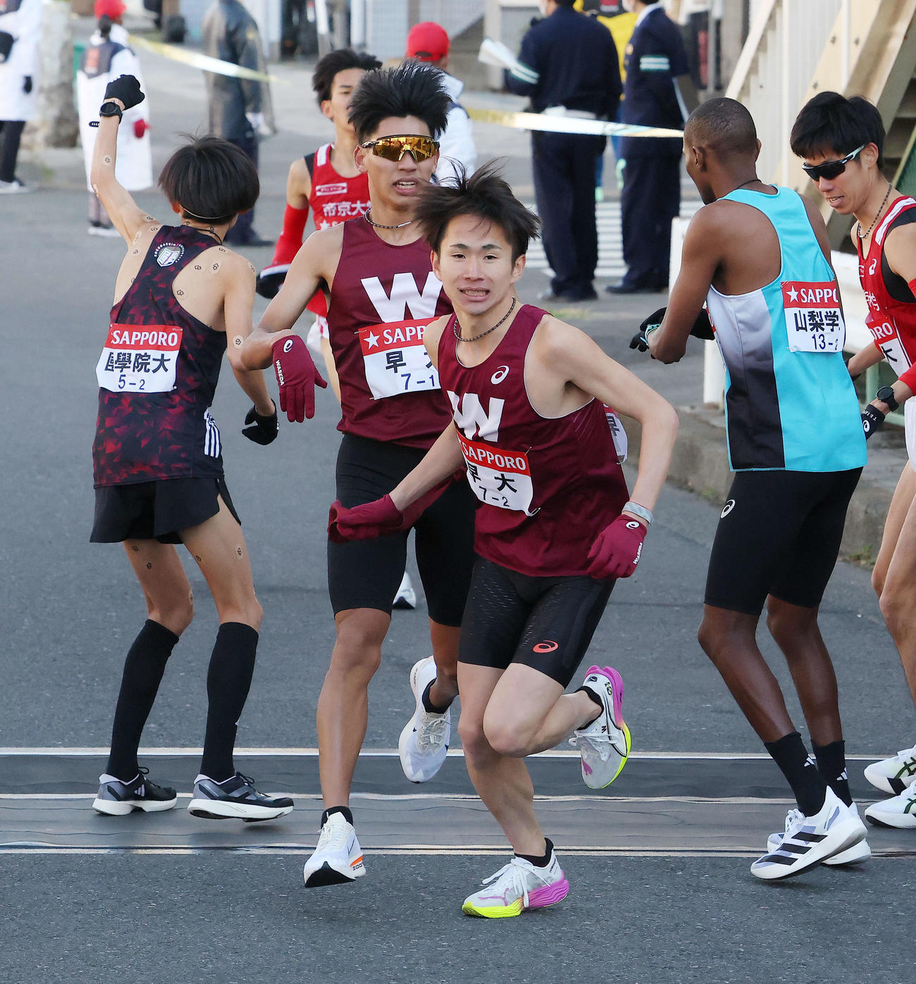鶴見中継所を4位でタスキリレーする早大1区間瀬田（左から2人目）と2区山口智（撮影・河田真司）