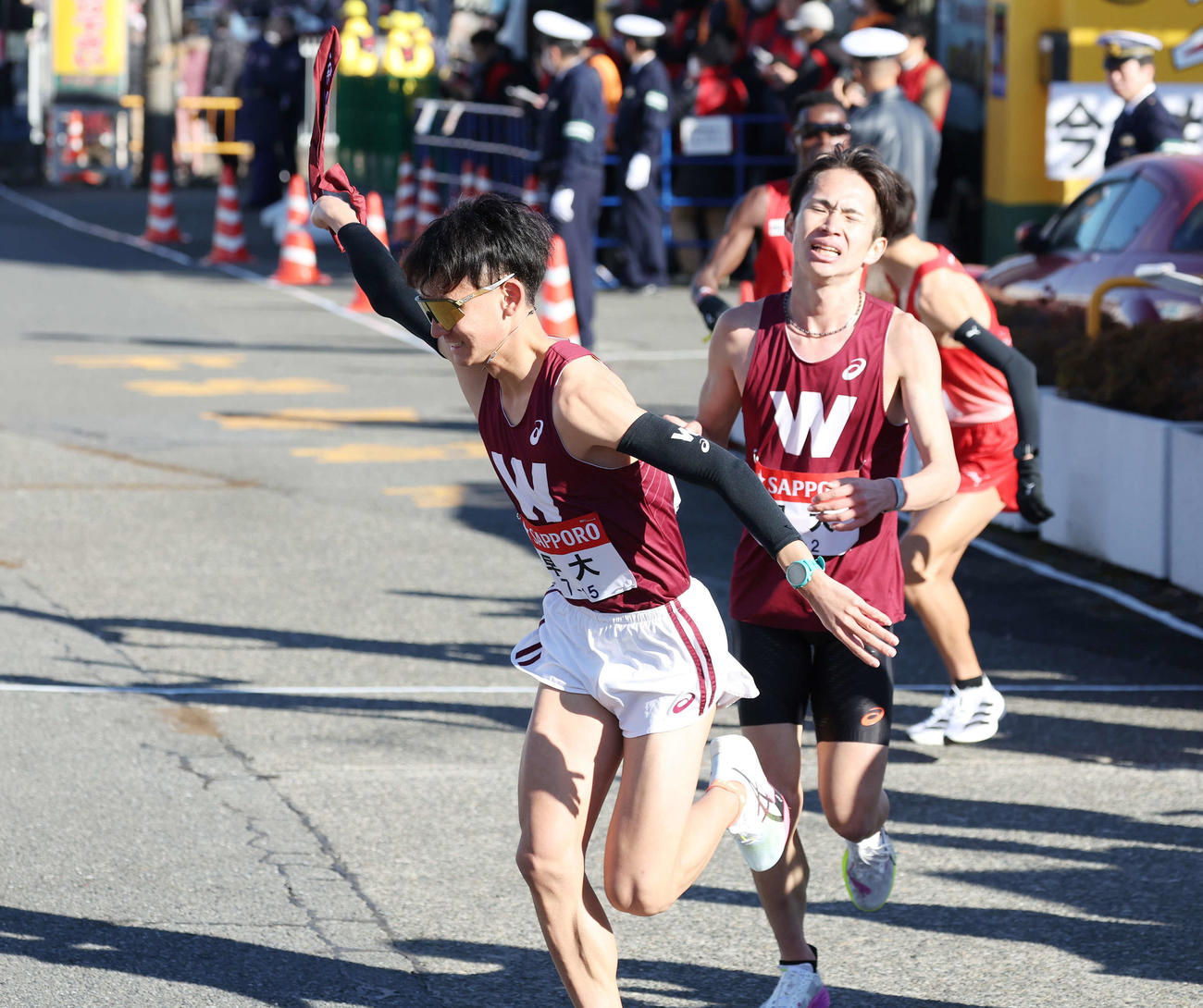 戸塚中継所で早大3区山口竣（左）は2区山口智からタスキを受け駆け出す（撮影・宮地輝）