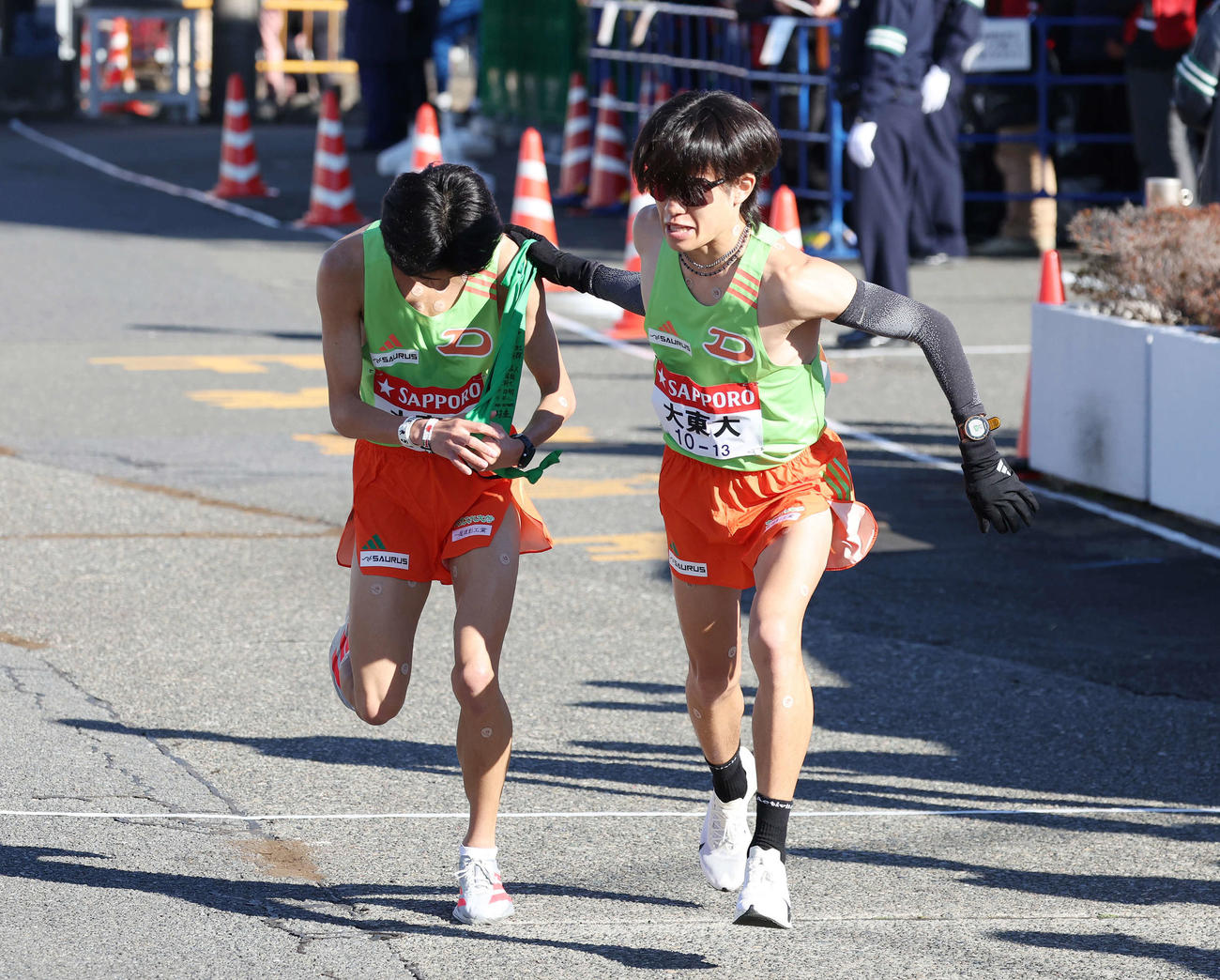 戸塚中継所で大東文化大3区入浜（右）は2区棟方からタスキを受け駆け出す（撮影・宮地輝）