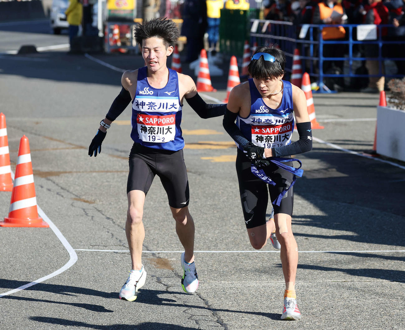 戸塚中継所で神奈川大2区宮本（左）は3区酒井にタスキをつなぐ（撮影・宮地輝）