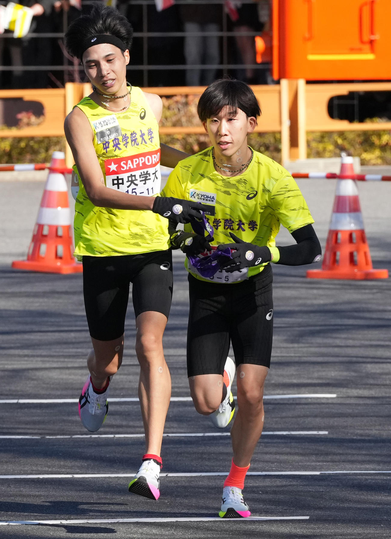 中央学院大4区太田（左）は5区柴田に小田原中継所でたすきを渡す（撮影・鈴木みどり）