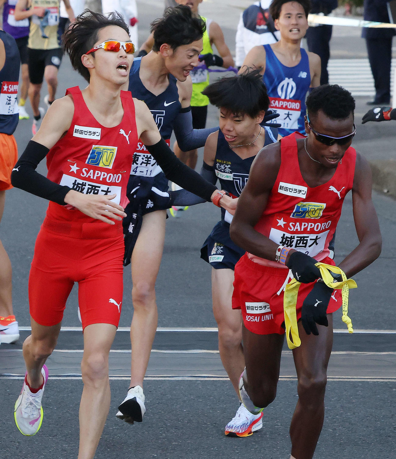 鶴見中継所を11位でタスキリレーする東洋大1区小林（左）と2区緒方（撮影・河田真司）