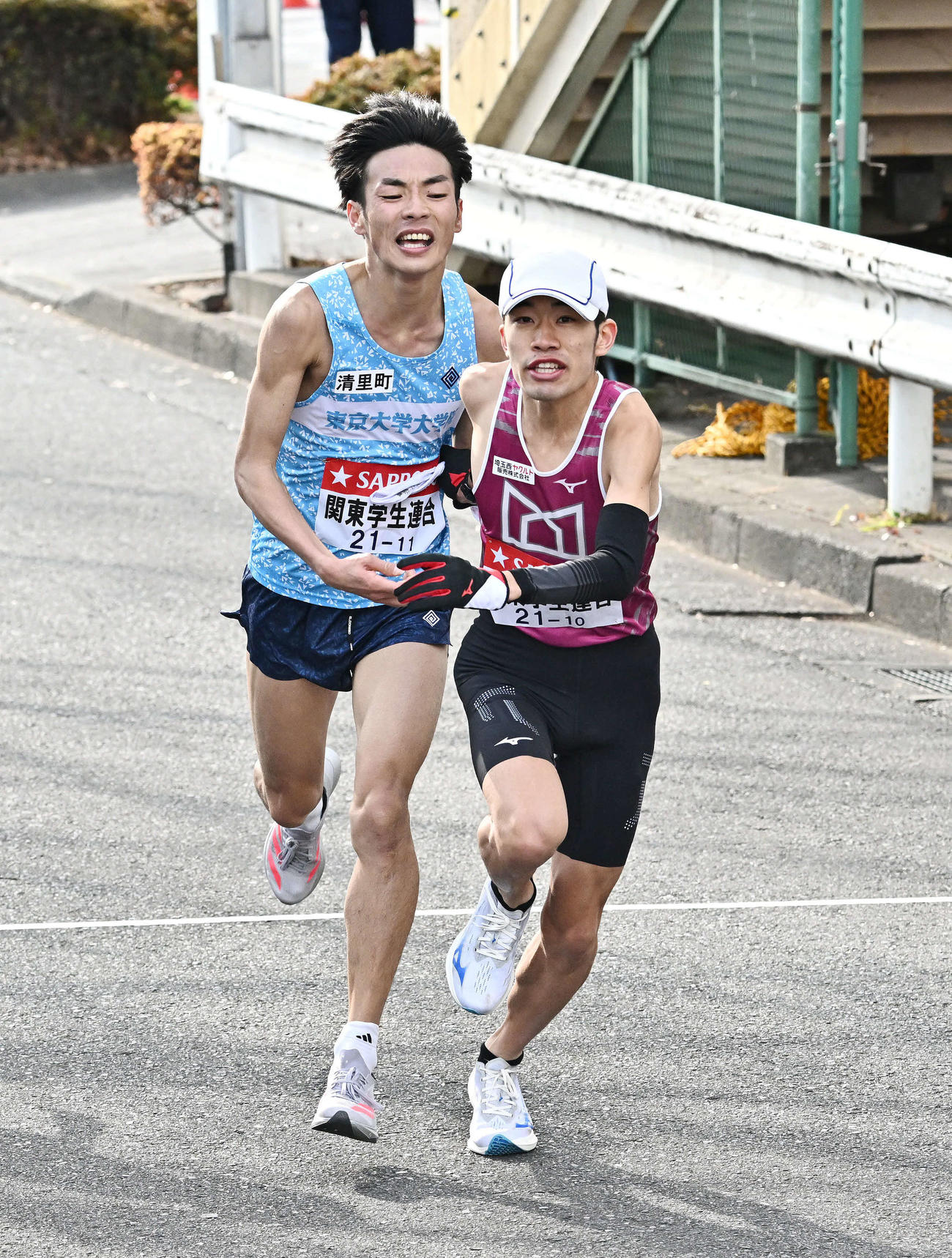 鶴見中継所でタスキリレーする関東学生連合の9区東大院・古川（左）と10区武蔵野学院大・福本（撮影・滝沢徹郎）