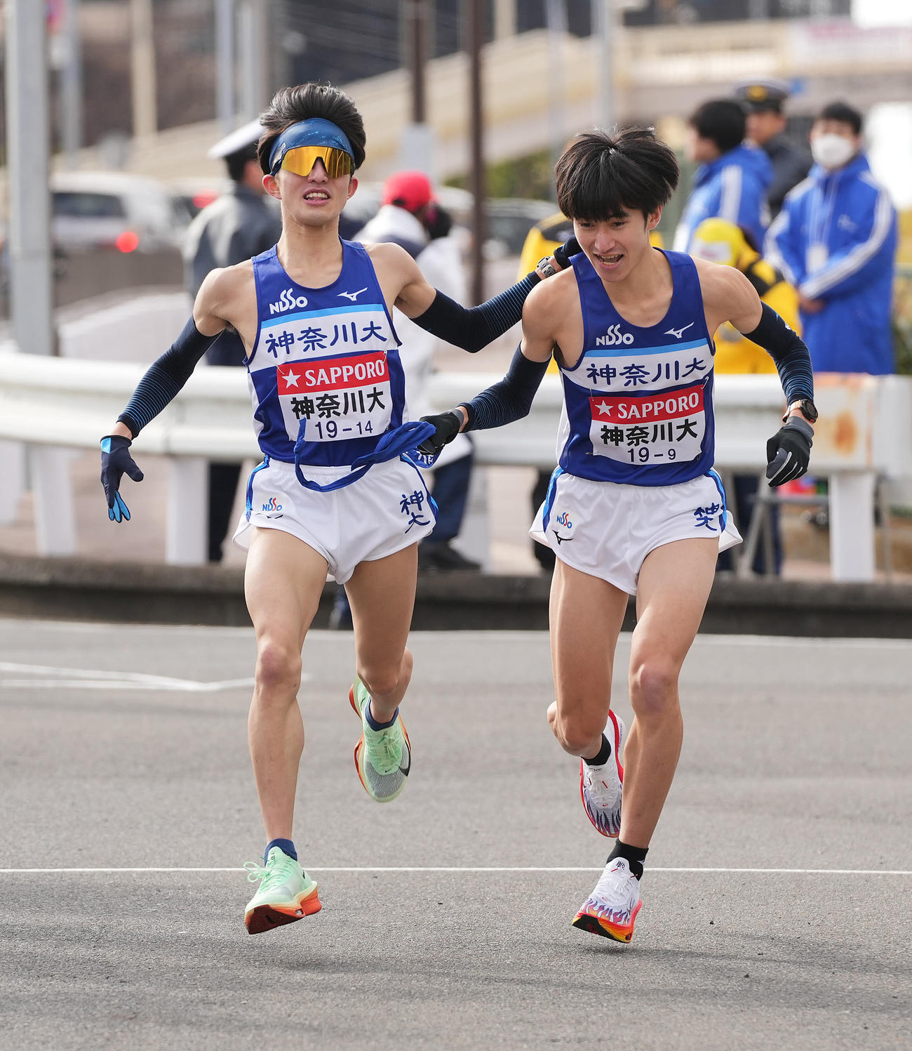 戸塚中継所でタスキリレーする神奈川大8区西坂（左）と9区志食（撮影・垰建太）