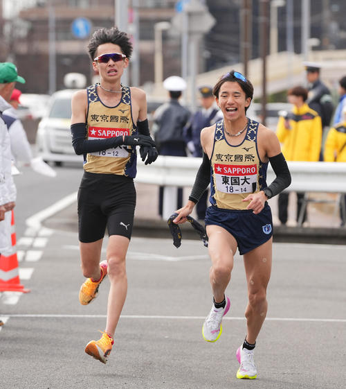 戸塚中継所でタスキリレーする東京国際大8区益田（左）と9区菅野（撮影・垰建太）