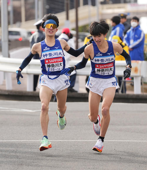 戸塚中継所でタスキリレーする神奈川大8区西坂（左）と9区志食（撮影・垰建太）