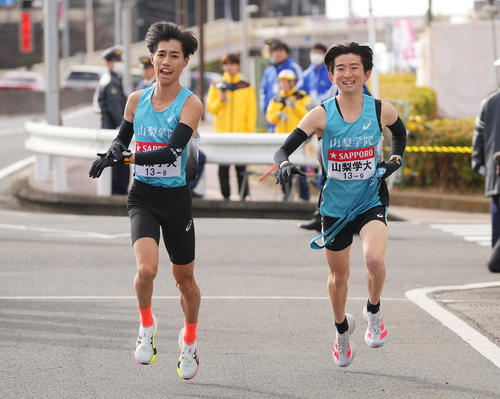 戸塚中継所でタスキリレーする山梨学院大8区阿部（左）と9区徳田（撮影・垰建太）