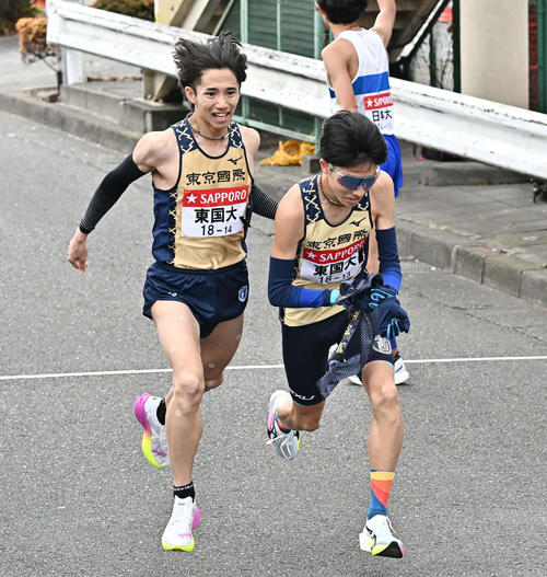 鶴見中継所でタスキリレーする東京国際大の9区菅野（左）と10区大村（撮影・滝沢徹郎）