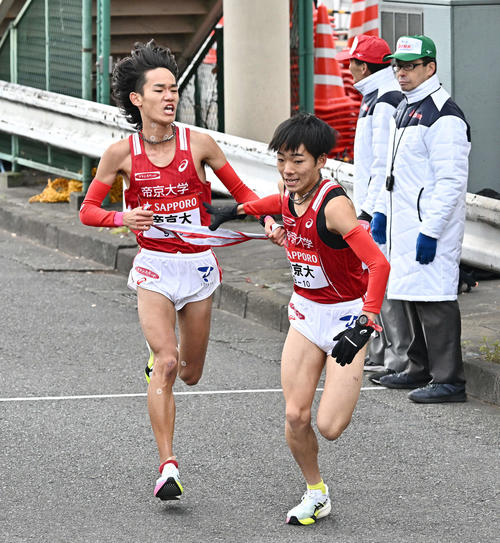 鶴見中継所でタスキリレーする帝京大の9区小林大（左）と10区小林咲（撮影・滝沢徹郎）