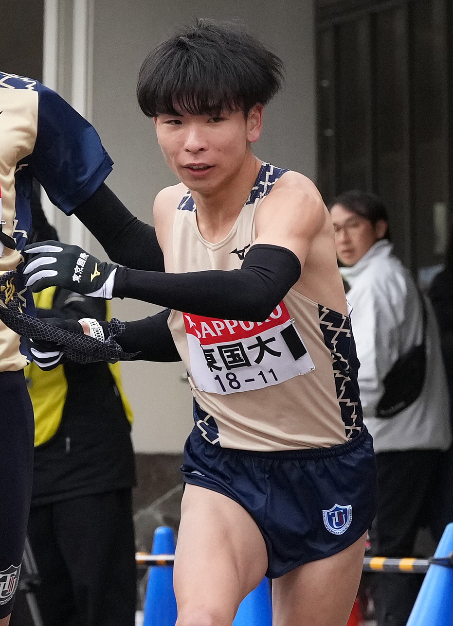 小田原中継所で東京国際大6区中山からたすきを渡される7区冨永（撮影・鈴木みどり）