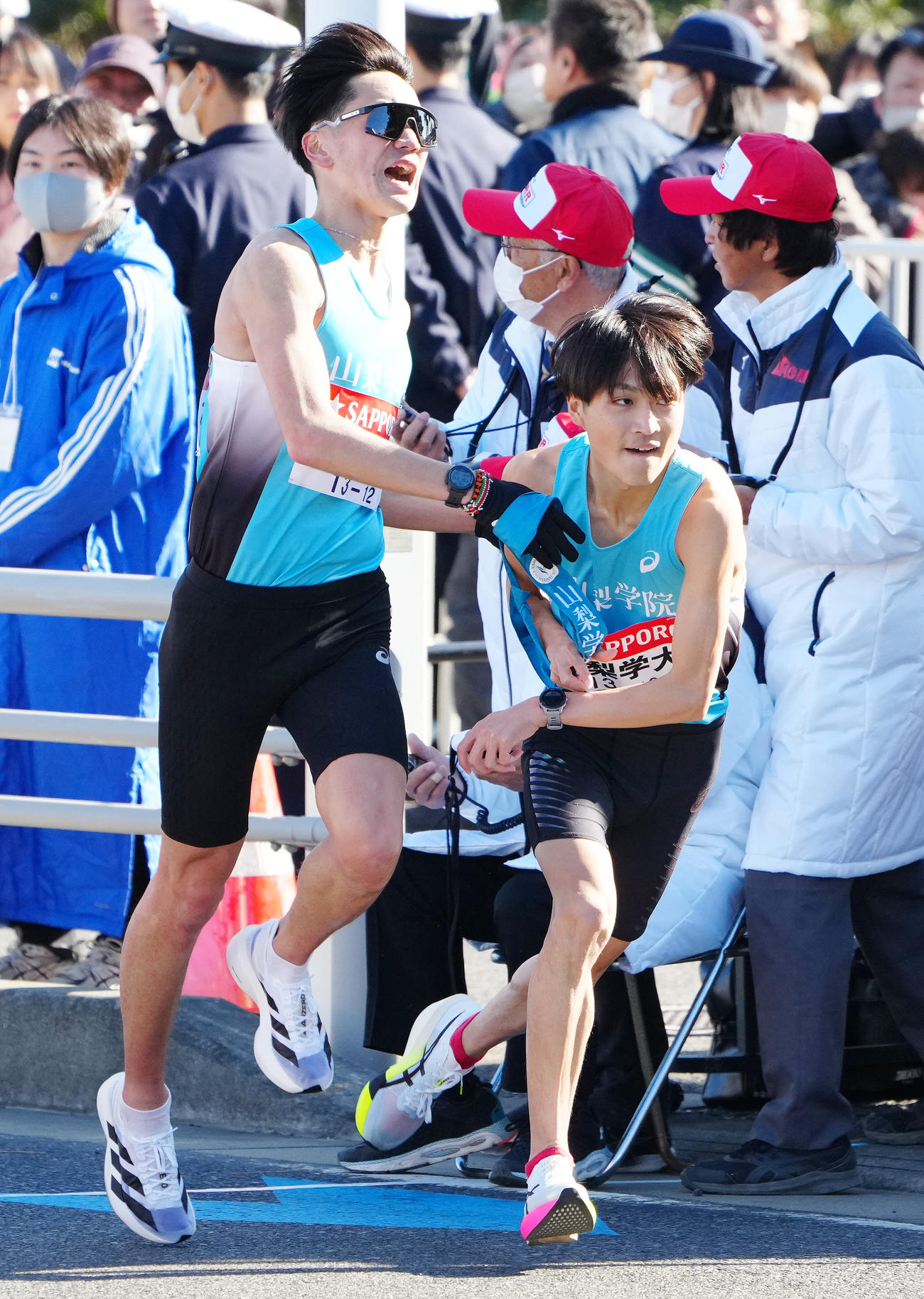 平塚中継所でタスキをつなぐ山梨学院大3区村上（左）と4区和田（撮影・江口和貴）