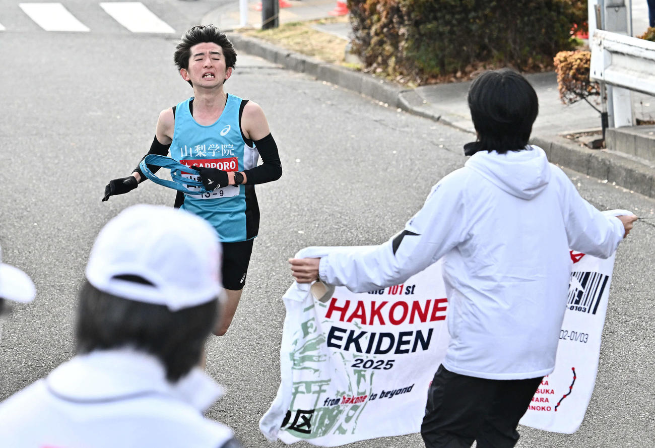 繰り上げスタート後に鶴見中継所にたどり着く山梨学院大9区徳田（左）（撮影・滝沢徹郎）