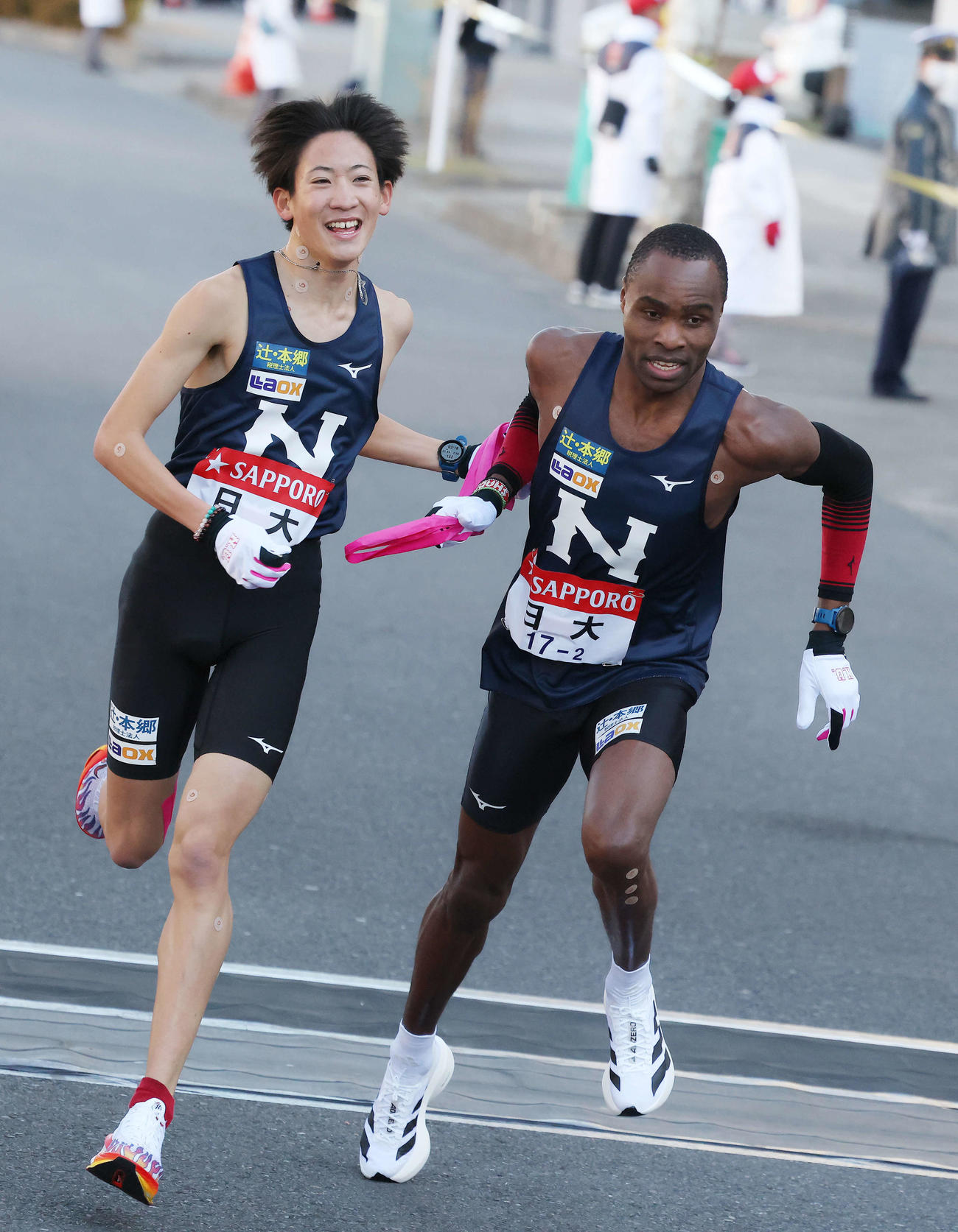 鶴見中継所を19位でタスキリレーする日大1区安藤（左）と2区キップケメイ（撮影・河田真司）