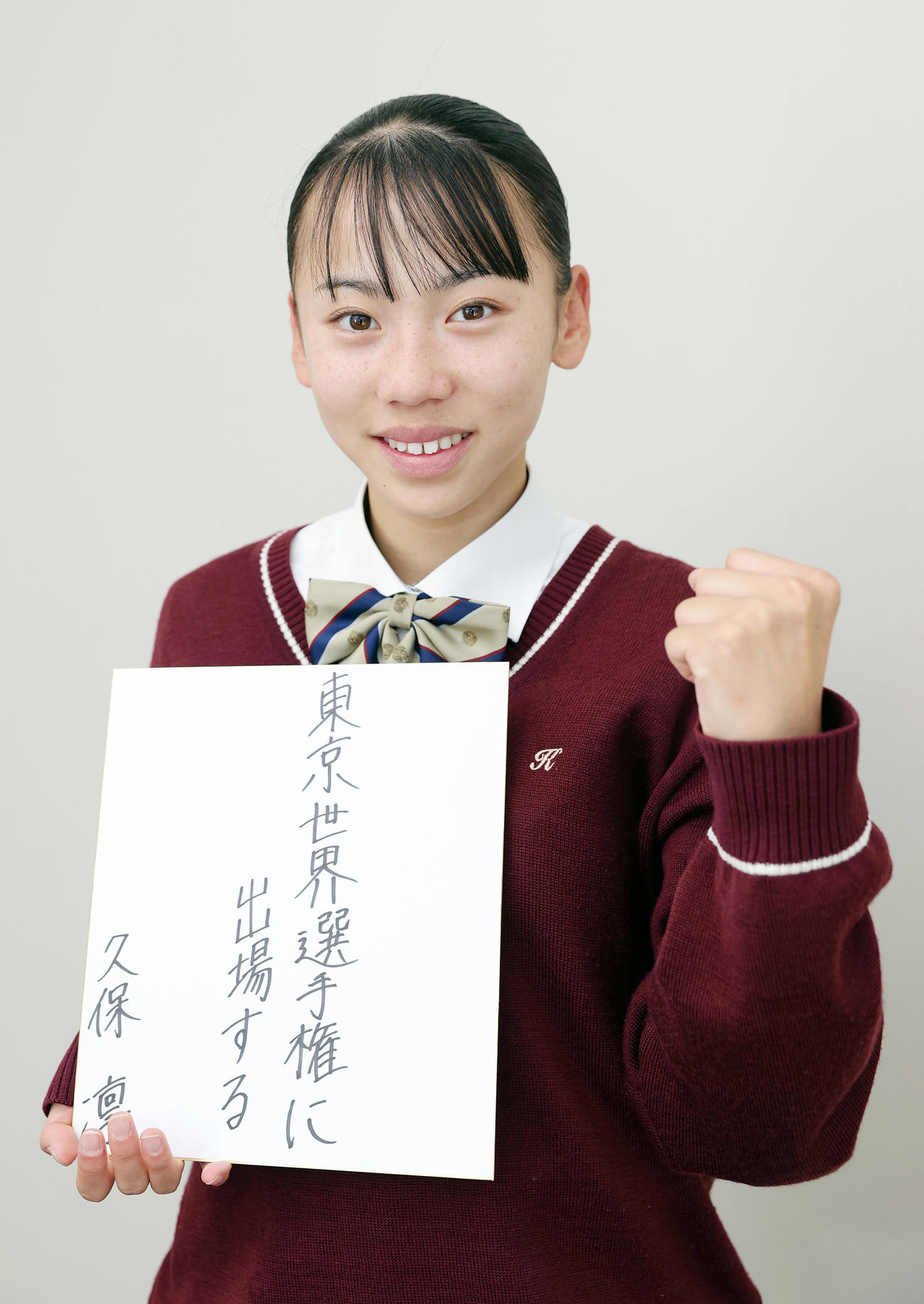 2025年の目標を記した色紙を手にガッツポーズする久保凜（撮影・前田充）＝2024年12月3日、東大阪大学敬愛高等学校