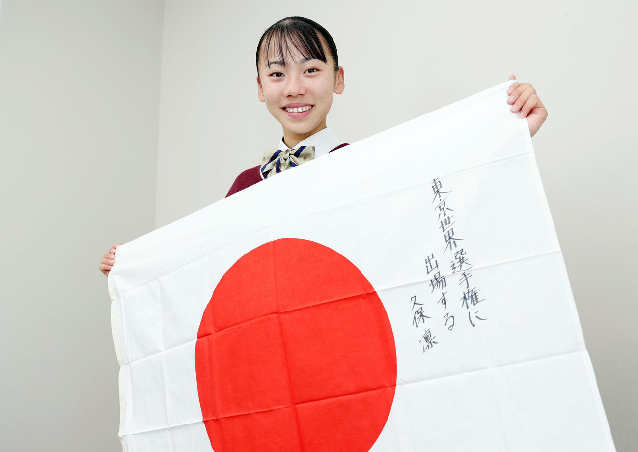 2025年の目標を記した日の丸を手に笑顔を見せる久保凜（撮影・前田充）＝2024年12月3日、東大阪大学敬愛高等学校