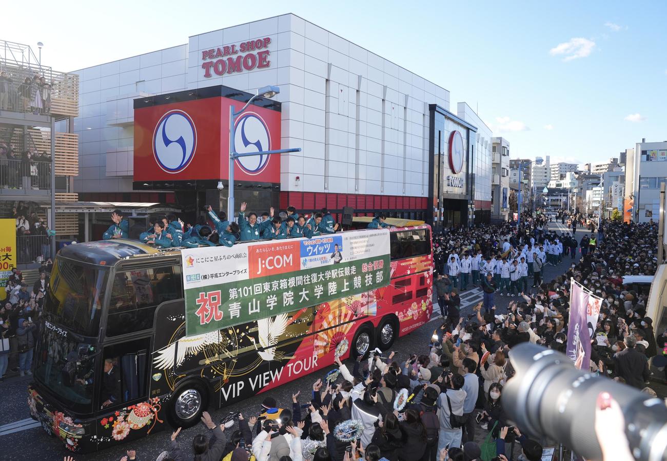 箱根駅伝優勝パレードで沿道に集まった多くのファンに手を振る原監督（中央）ら青学大の選手たち（撮影・垰建太）