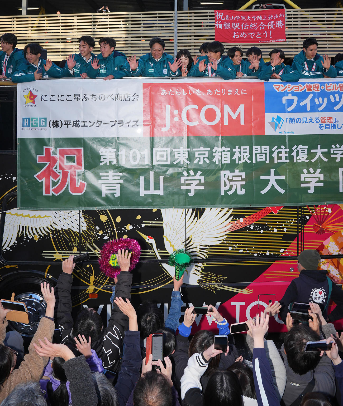 箱根駅伝優勝パレードで沿道のファンに手を振る青学大・原監督（中央）ら選手たち（撮影・垰建太）