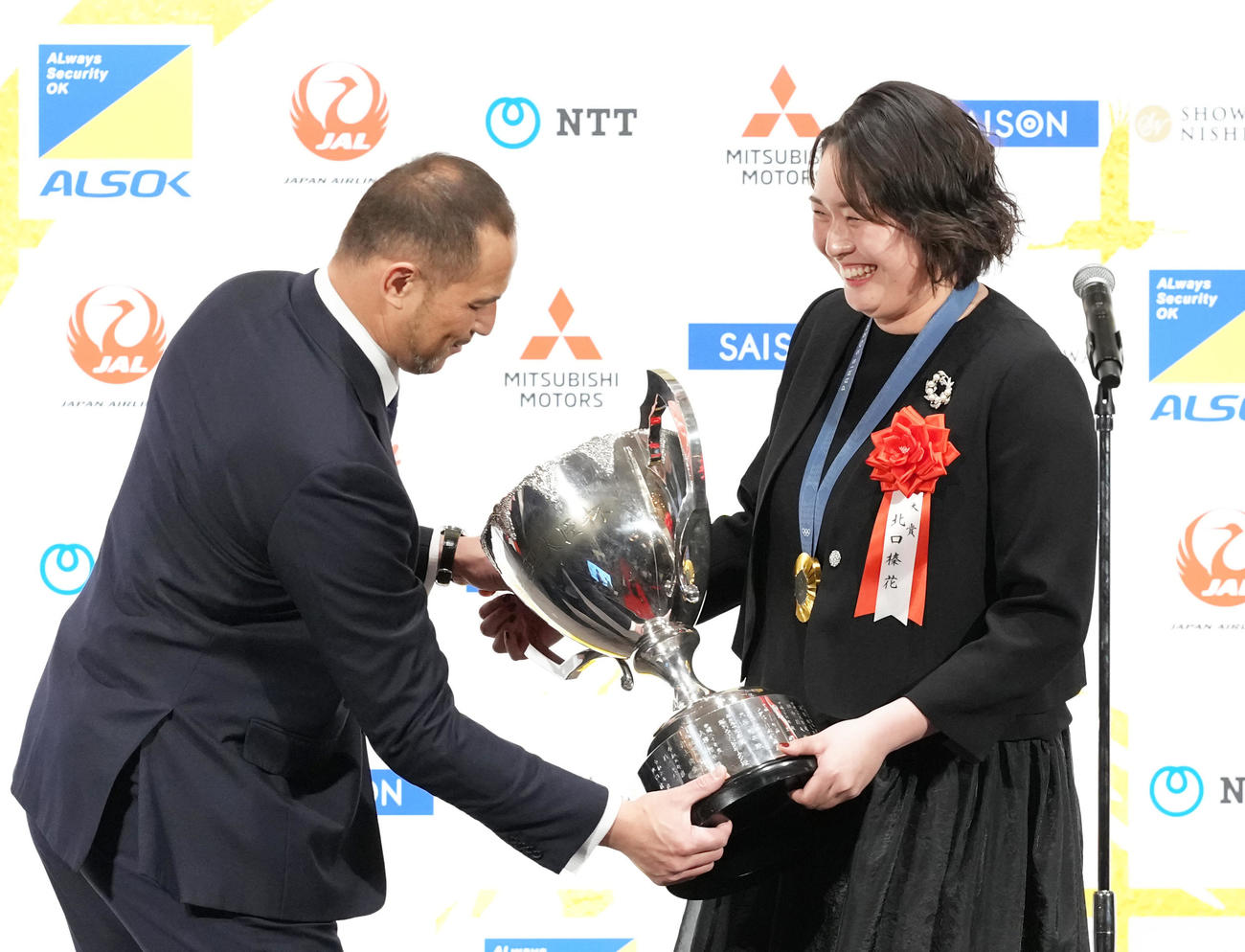 日本プロスポーツ大賞を受賞し、スピーチに臨む北口（右）はトロフィーを室伏スポーツ庁長官に預け持ってもらう（撮影・足立雅史）