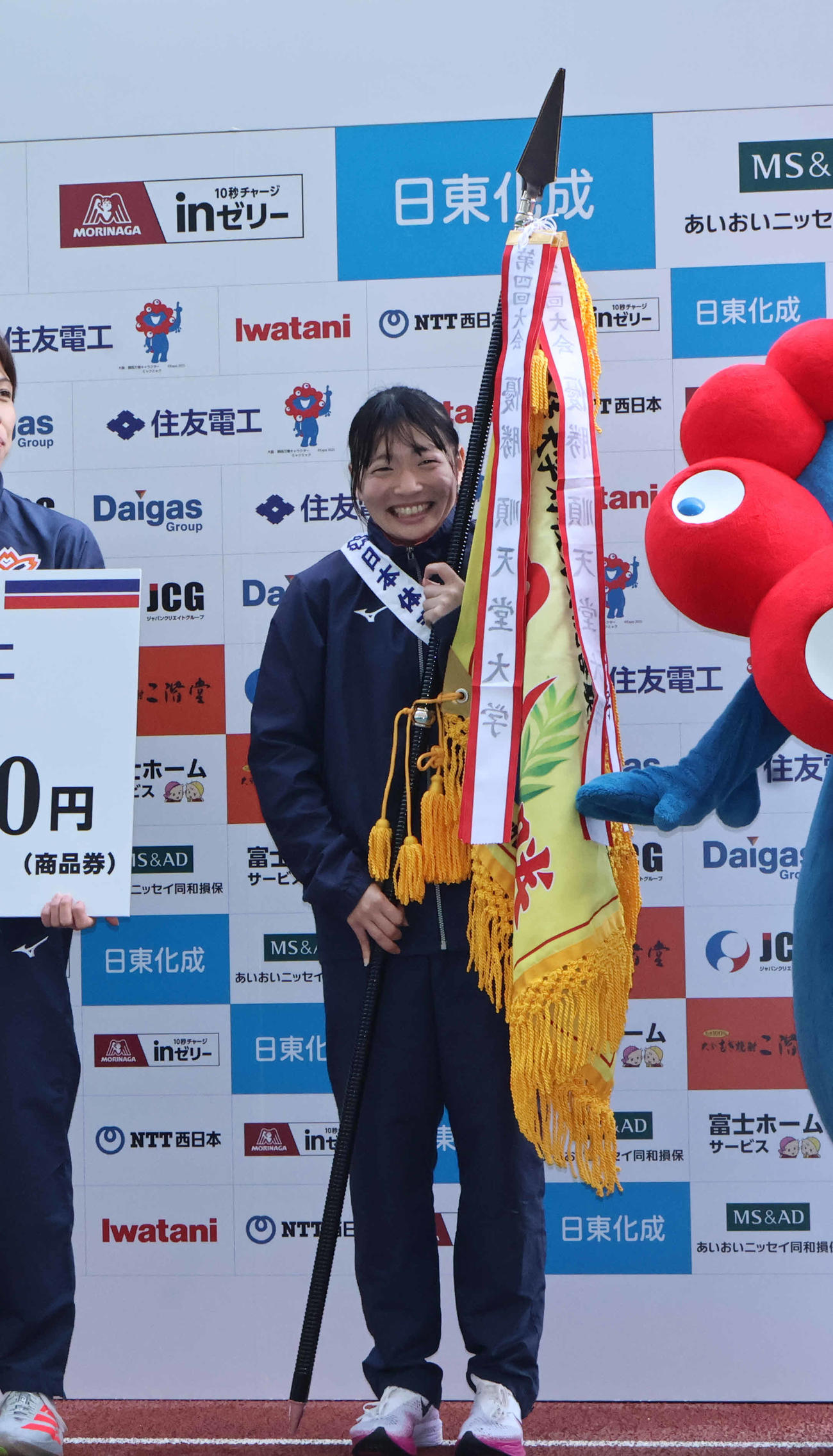 優勝旗を持ち笑顔の日体大6区の尾方唯莉（撮影・竹本穂乃加）