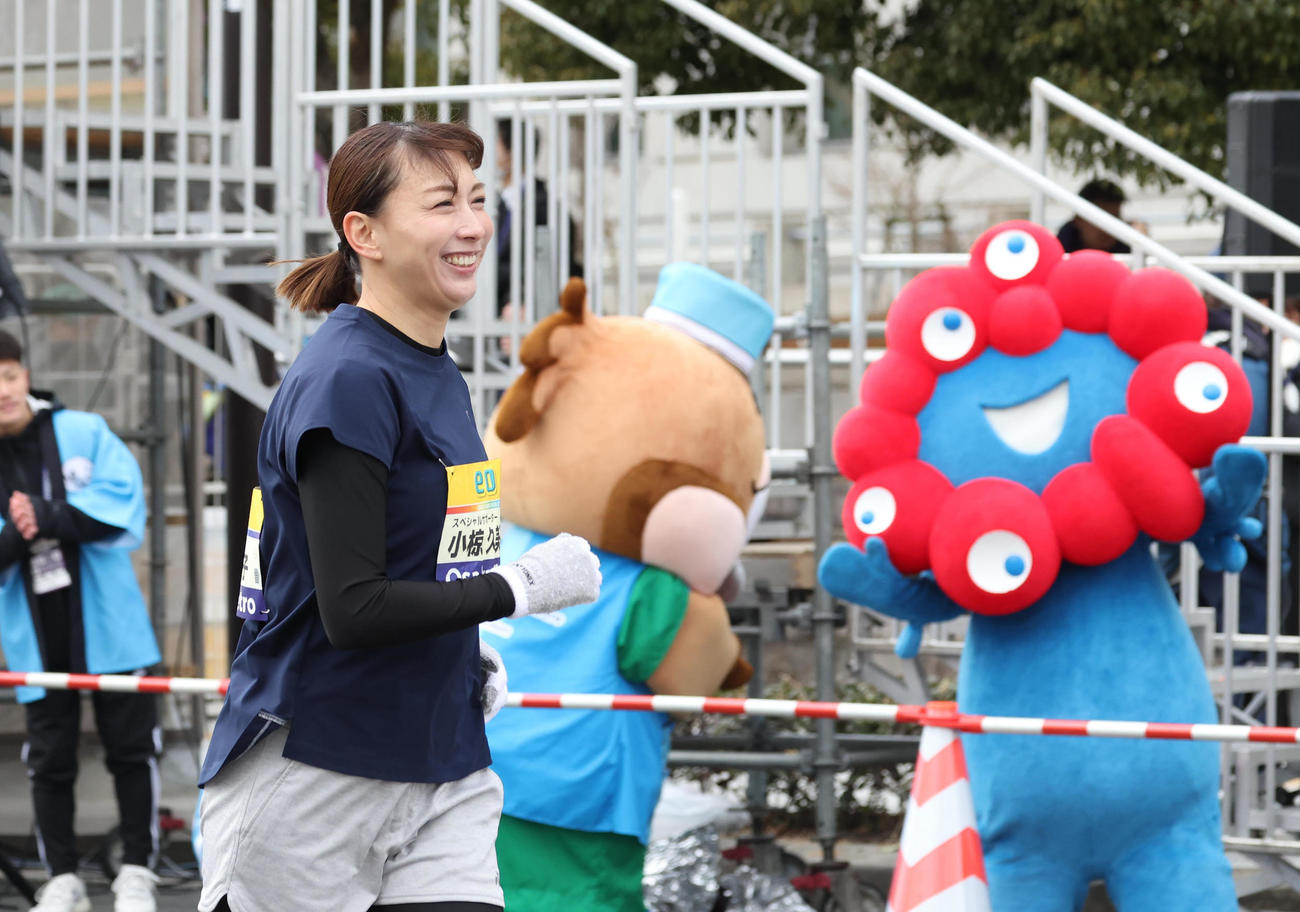 ミャクミャク（右）の応援をバックにスタートする小椋久美子（撮影・白石智彦）