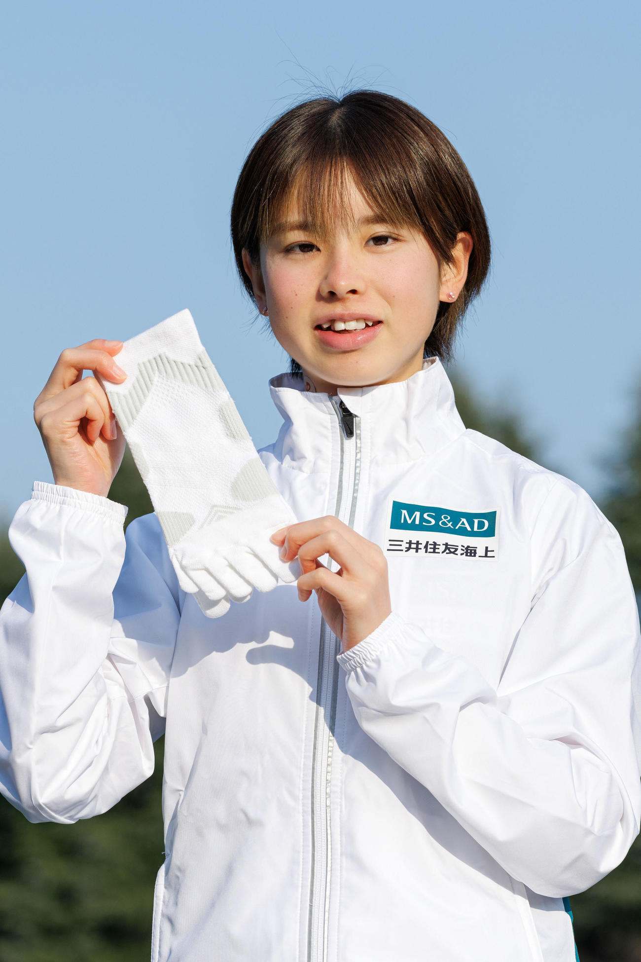 ファイテン株式会社とアドバイザリー契約を結び、三井住友海上のウエア姿で同社の製品を手にする陸上女子長距離の不破聖衣来（同社提供）