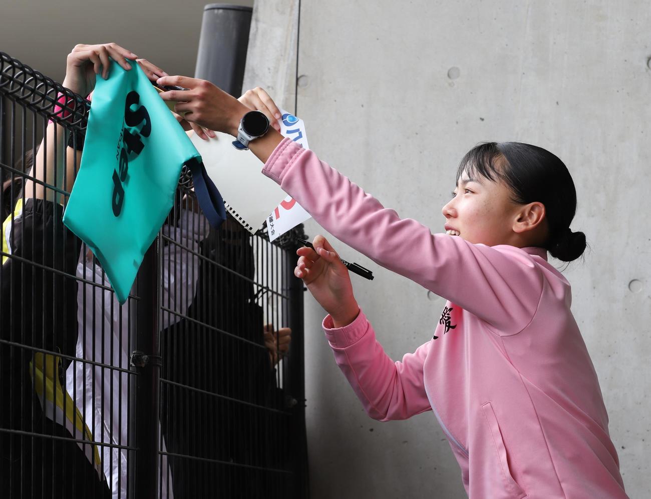 金栗記念選抜陸上中長距離大会　女子800メートルのレース後に子どもたちからのサインに応じる久保凛（撮影・藤塚大輔）