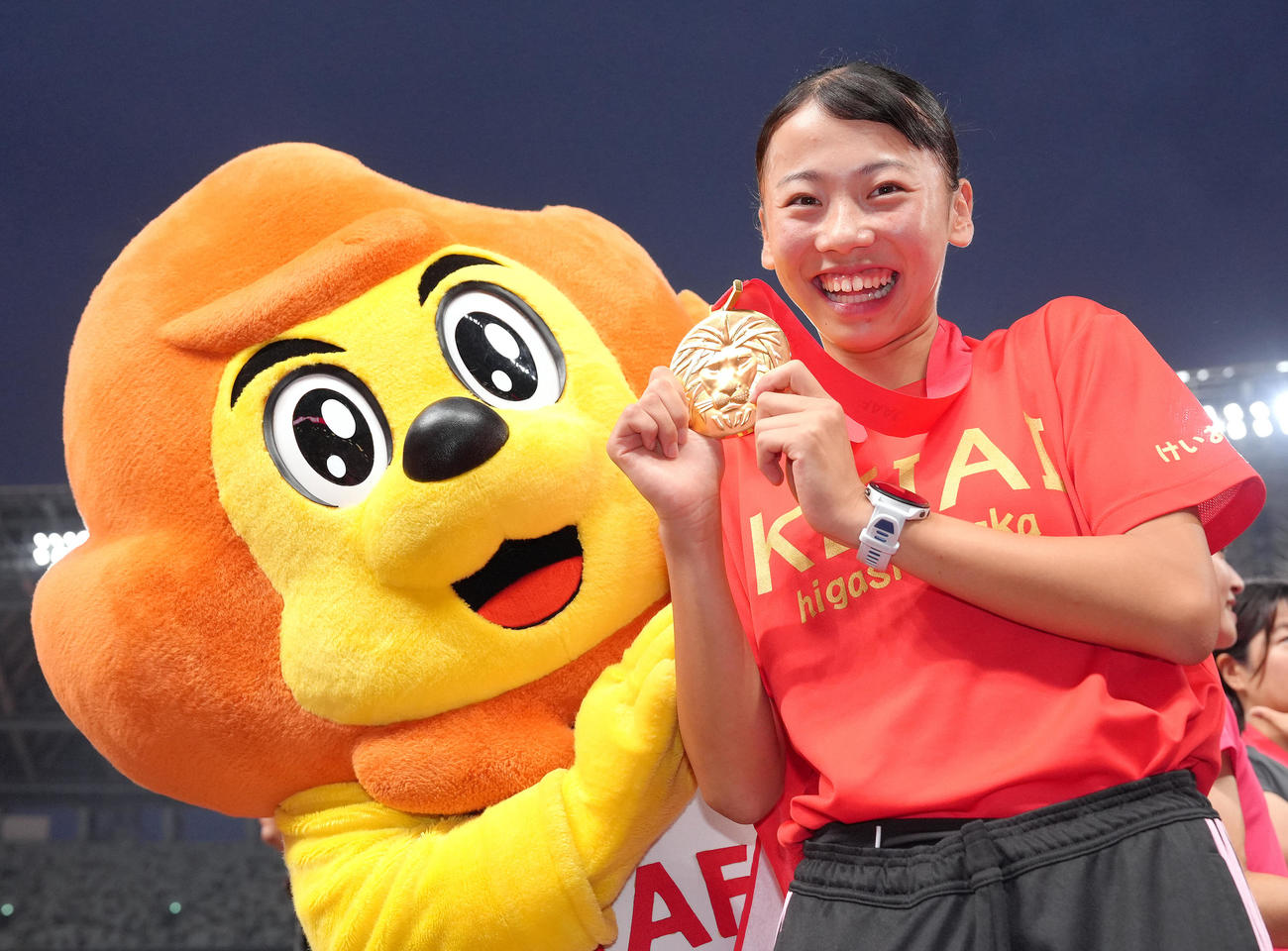 女子800メートル決勝を日本新記録で優勝した久保は日本陸上競技連盟マスコット「アスリオン」の祝福に笑顔を見せる（撮影・足立雅史）