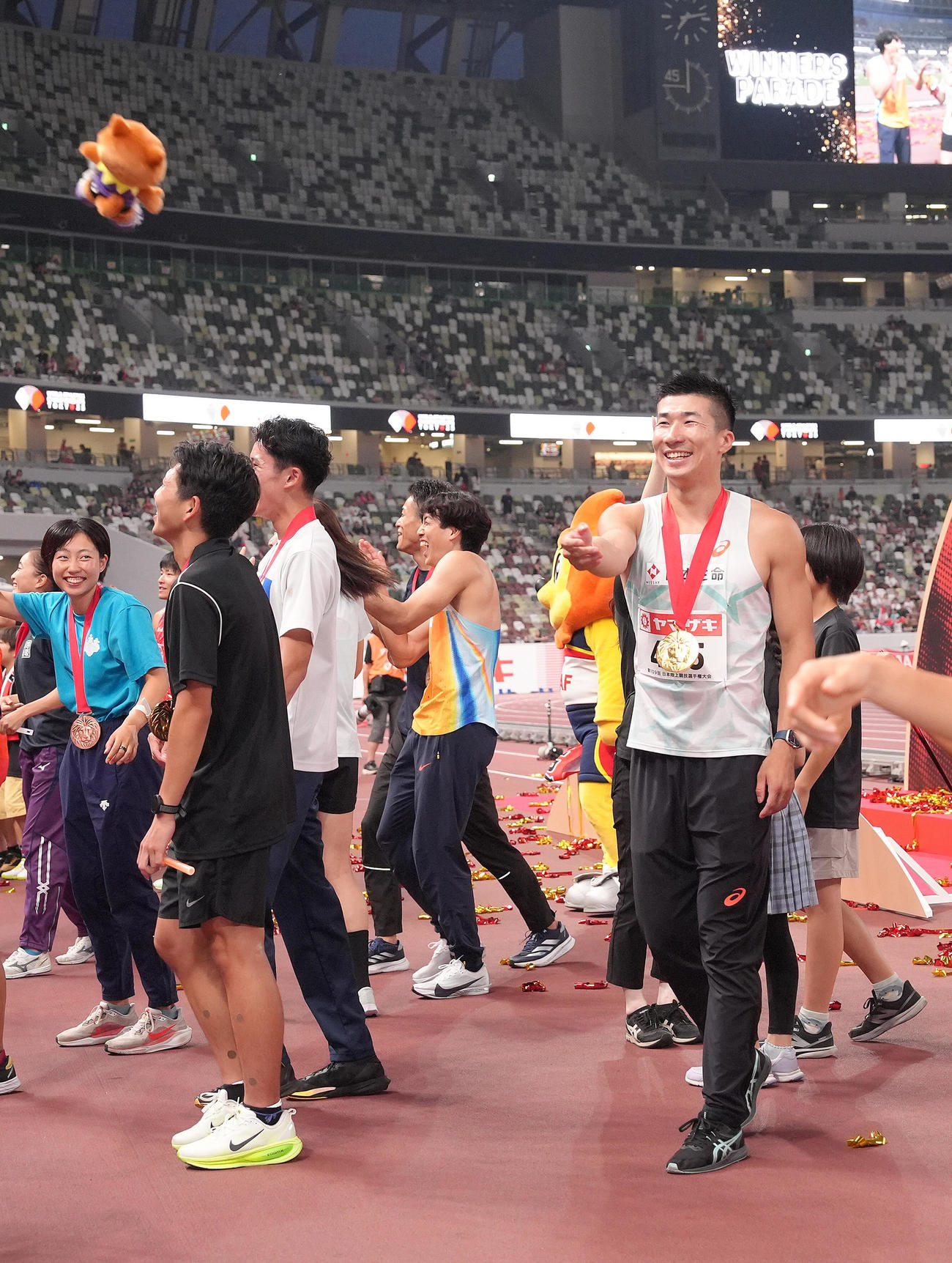 男子100メートル決勝で優勝した桐生はレース後のウィナーズパレードで笑顔でファンにぬいぐるみを投げ入れる（撮影・足立雅史）